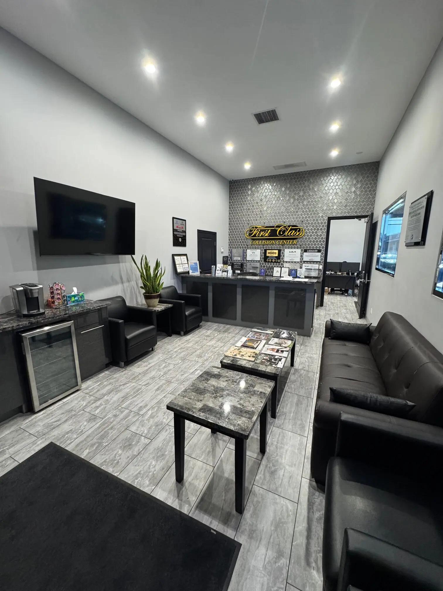 Modern waiting area with black leather sofas and a TV.