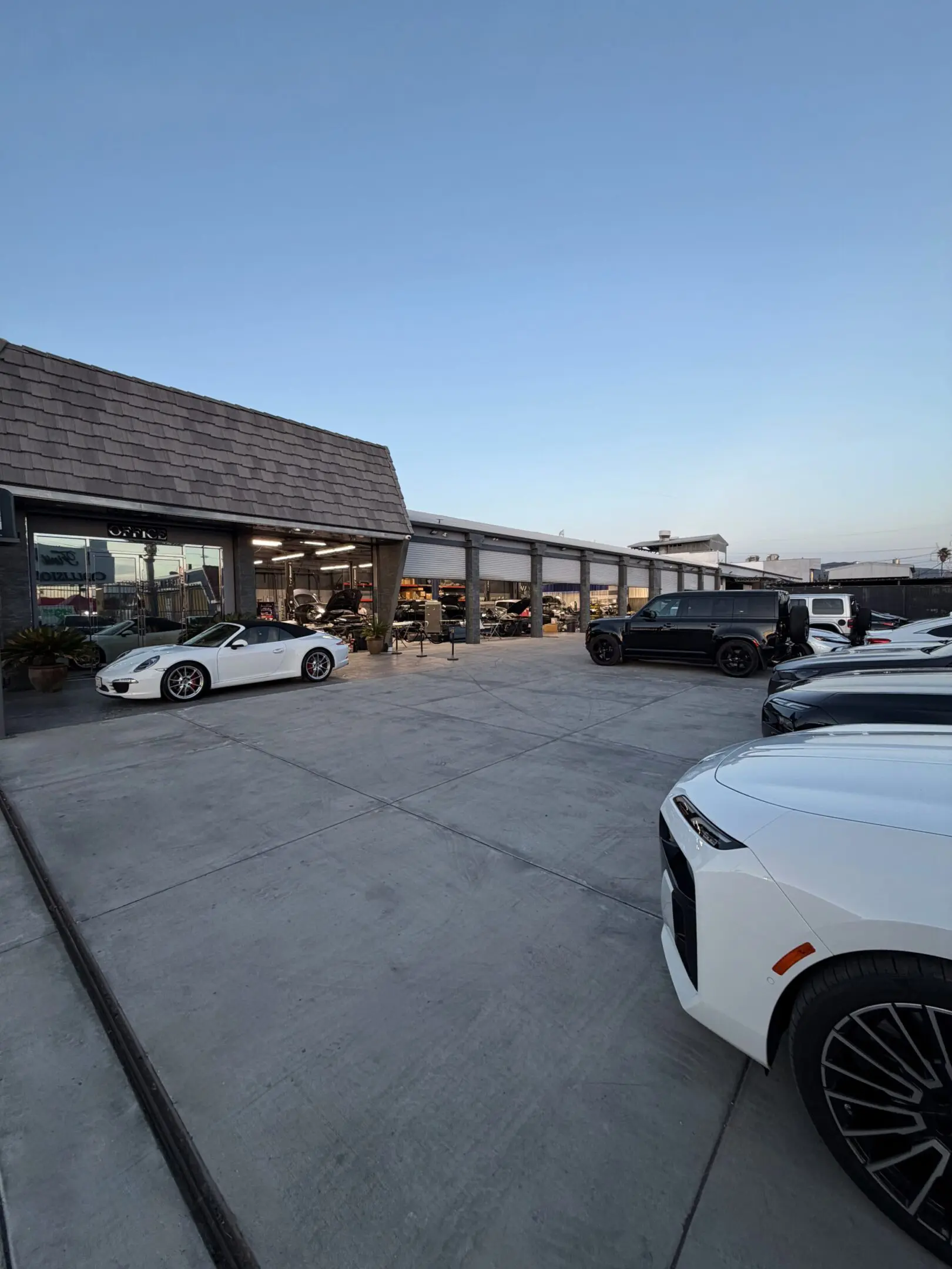 A parking lot with several modern cars and buildings in the background.