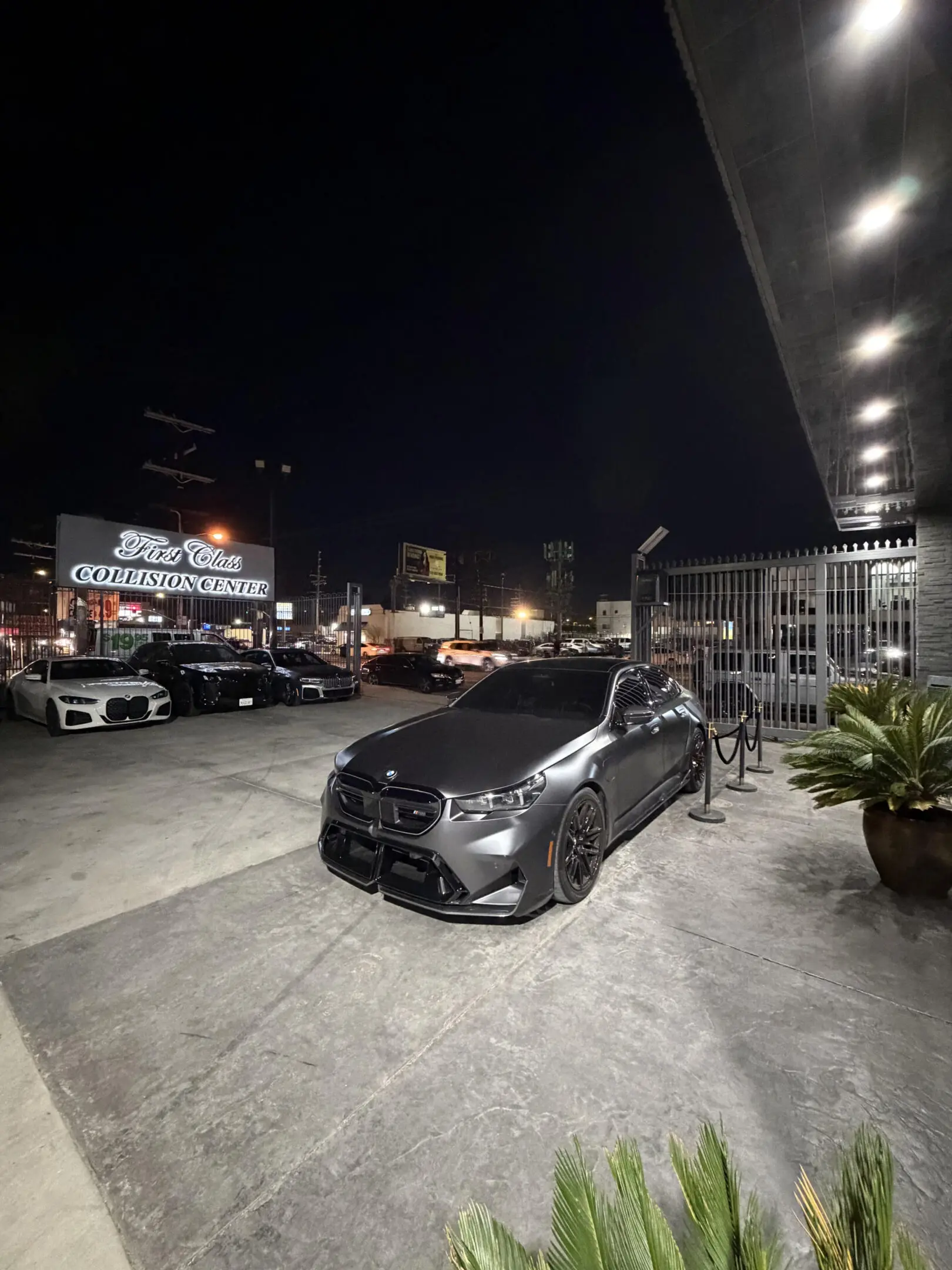 Black car parked on a city street at night with illuminated surroundings.